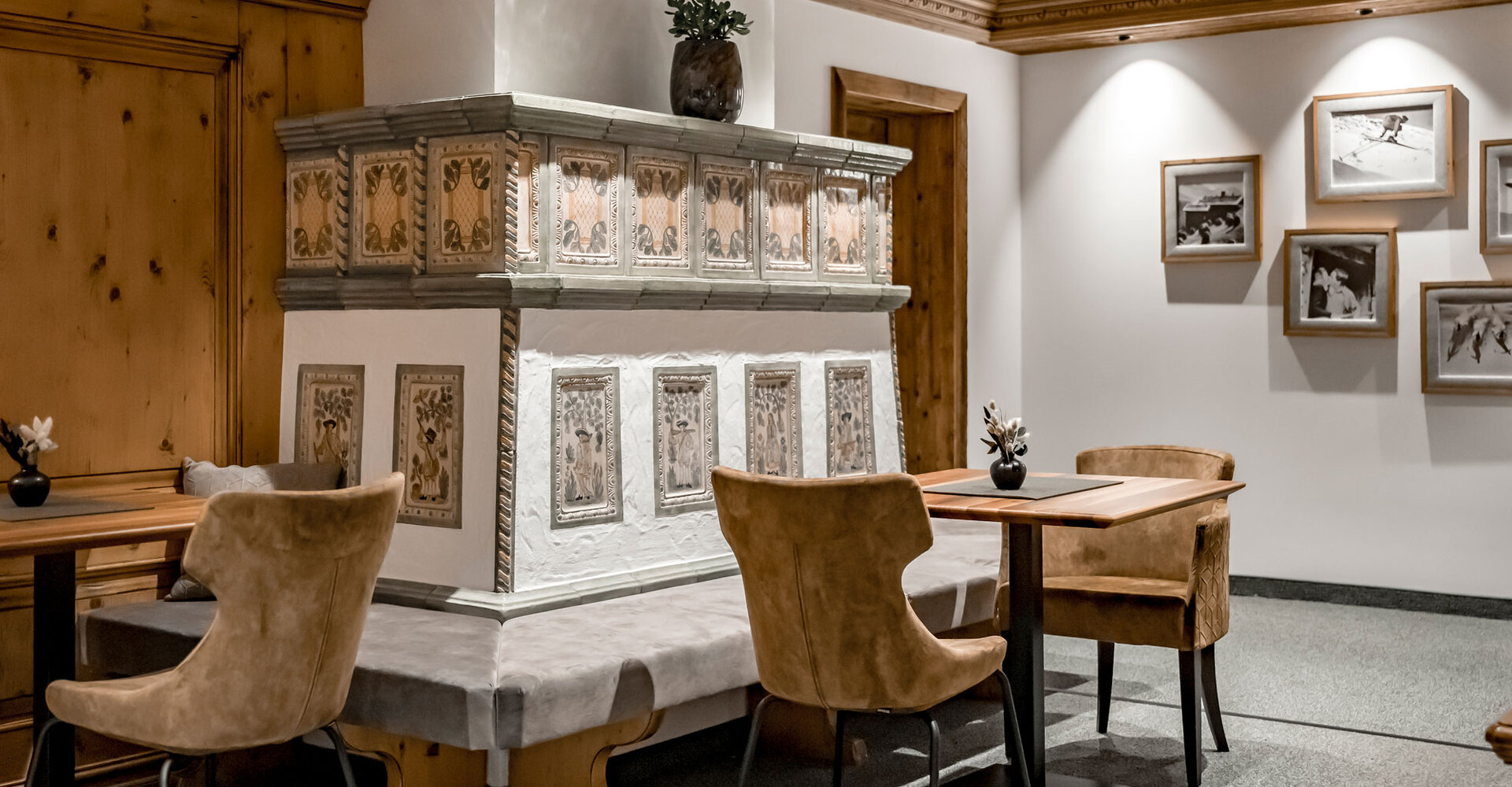 A stylish hotel bar featuring a vase full of flowers on the counter, shelves stocked with bottles and glasses in the background and a section of a mountain painting on the left.