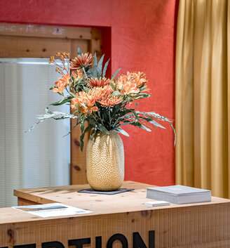 A reception desk decoerated with a vase of fresh flowers standing on the counter. 