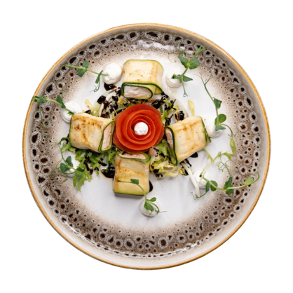 A gourmet dish featuring four rolls wrapped in zucchini, an eye-catching tomato rose, leafy greens, mushrooms, dollops of white sauce and microgreens, artfully arranged on a decorative ceramic plate.